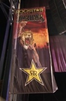 Rockstar Main Stage banner photo by Strati Hovartos Rockstar Main Stage banner, featuring an image of a lion's head on a male singer's body, fist pumped in the air, in front of a fiery backdrop. Photo by Strati Hovartos.