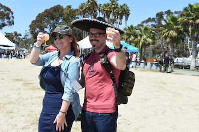 Sombrero-clad patrons enjoying craft beer samples on the beach at Sabroso 2017