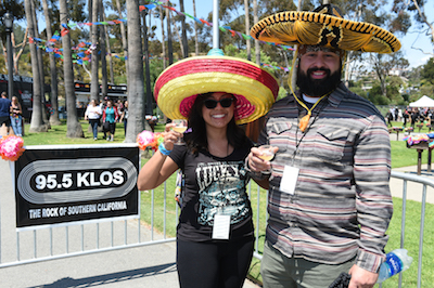 Sombrero-clad Sabroso attendees enjoying craft beer samples in front of a KLOS banner